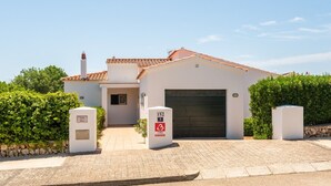 A two-story building with a tiled roof, a garage, and a paved entrance area. - Villa Casa Nova, Piscina, Wifi, AC gratis (Sant Lluís)