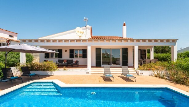 Uma casa moderna com piscina, área de estar externa e céu limpo.