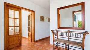 A hallway with a wooden door, a bench, and a mirror on the wall. - Villa Casa Nova, Piscina, Wifi, AC gratis (Sant Lluís)