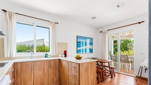 Uma cozinha moderna com armários de madeira, uma ilha integrada e um espaço de refeições com mesa e cadeiras.