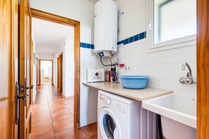 A hotel bathroom with a washing machine, a sink, and a blue basin. - Villa Casa Nova, Piscina, Wifi, AC gratis (Sant Lluís)