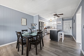 Enjoy meals in the well-equipped kitchen with stainless steel appliances and a dining area with a dark wooden table.