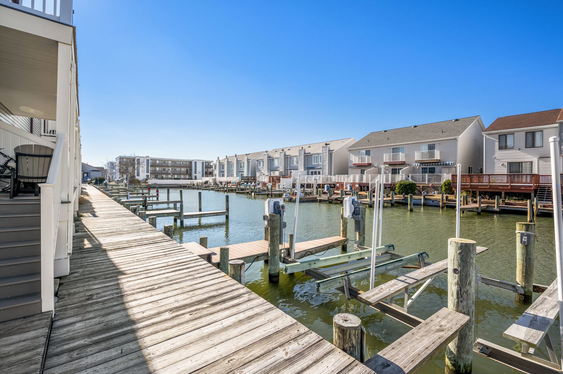 A waterfront property with a wooden dock extending into a calm waterway, surrounded by residential buildings with balconies and decks.
