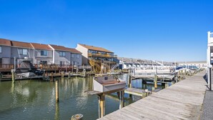 A marina with docked boats, wooden walkways, and residential buildings with balconies. - Sea Robin 207 by Seaside Vacations & Sales (Ocean City)