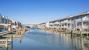 A canal lined with wooden docks and buildings with balconies. - Sea Robin 207 by Seaside Vacations & Sales (Ocean City)