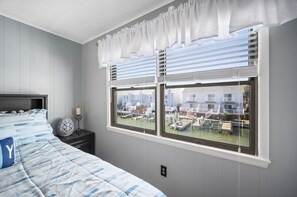 A bedroom with a bed, a nightstand, and a window with blinds.
