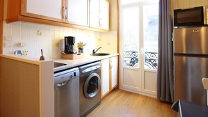 Eine kleine Küche mit Waschmaschine, Kaffeemaschine und Mikrowelle.