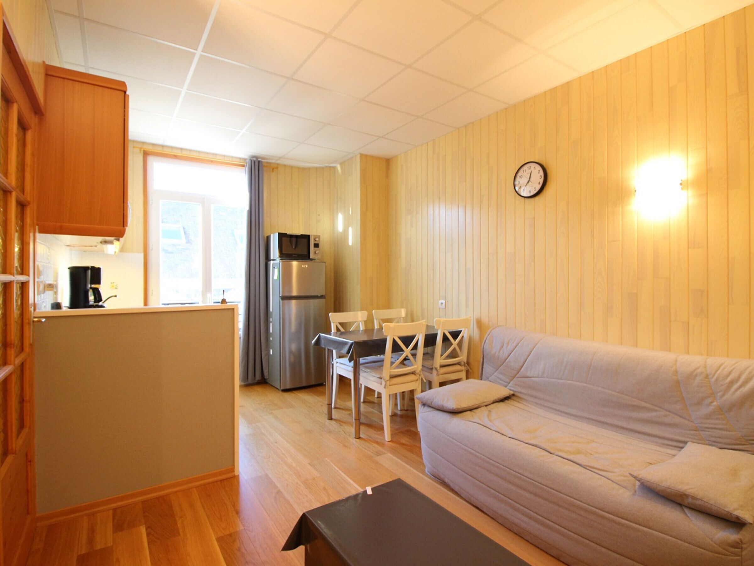 Un espacio habitable compacto con kitchenette, comedor y sofá.