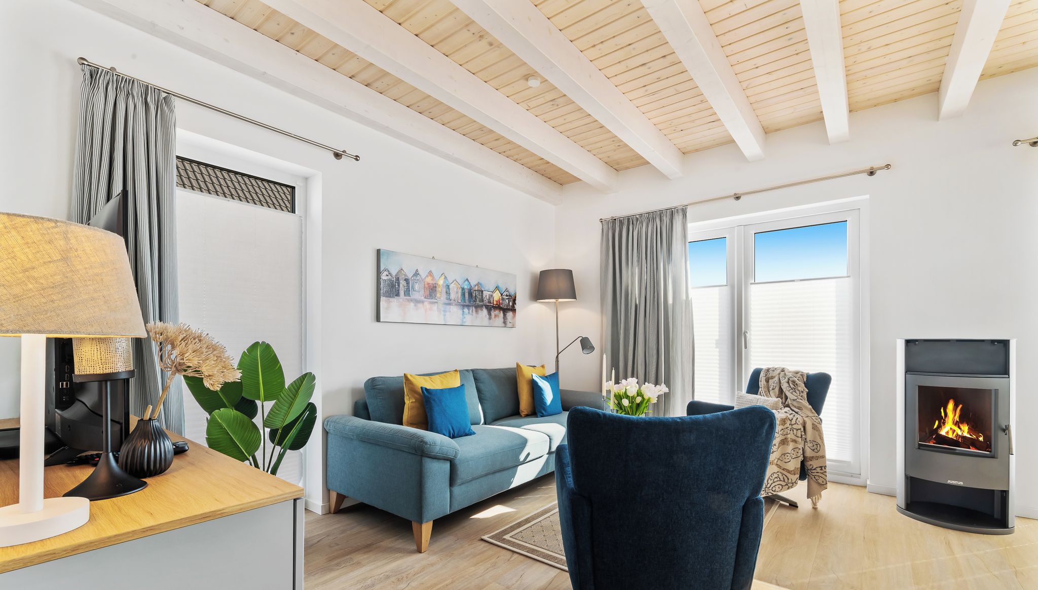 A modern living room with a sofa, armchairs, a fireplace, and a dining area.