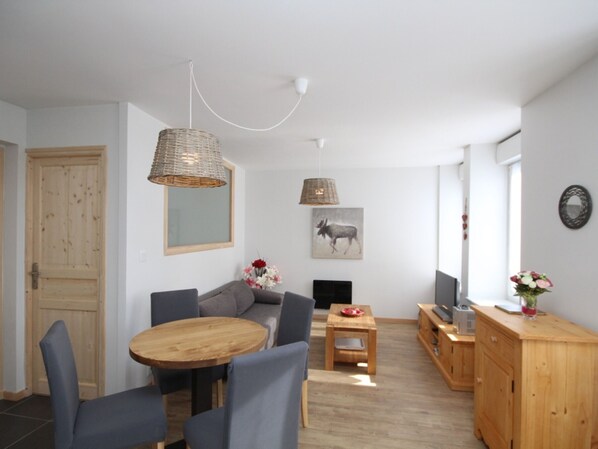 A cozy living room with a wooden dining table, grey sofas, and a wooden cabinet. - Mont-Dore: Cozy T2 with Wifi and TV Box (Mont-Dore)