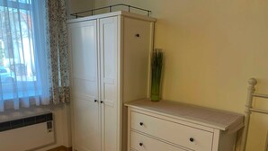 A room with a white wardrobe, a bedside table, and a window with floral curtains. - Studio mit Garten - Casa Lauda in Bad Vöslau (Bad Vöslau)
