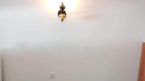 A red sofa with two cushions against a plain wall. - Beach Front Apartments (Sitia)