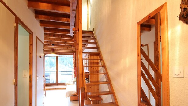 Un escalier en bois dans un couloir, avec vue sur un balcon.