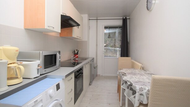 A compact kitchen with a washing machine, microwave, and coffee maker.