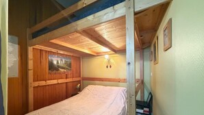 A bunk bed room with wooden walls, a framed picture, and a small desk. - 2* Studio in City Center with Balcony & WiFi (Mont-Dore)