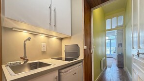 A compact kitchen with a sink, dishwasher, and a small refrigerator. - 2* Studio in City Center with Balcony & WiFi (Mont-Dore)