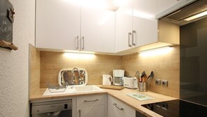 A modern kitchen with white cabinets, a dishwasher, a coffee maker, and a microwave.