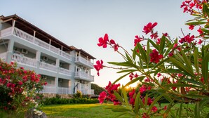 A multi-story building with balconies, surrounded by greenery and flowering plants. - Baywatch Apartments (Zakynthos)