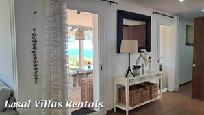 A hallway with a white console table, wicker baskets, a mirror, and a view of the outdoors. - Leo Street 96, Tossa de Mar-Lesal Villas Rentals Mar Azul (Santa maria de llorell, tossa de mar, gi)