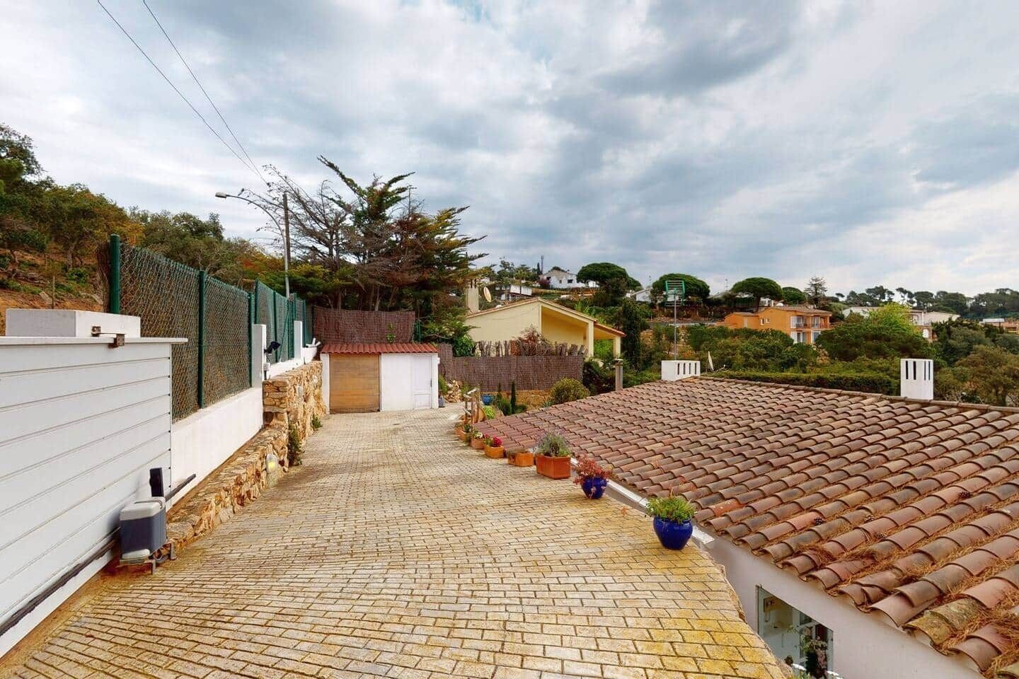 Una propiedad residencial con entrada pavimentada, un garaje pequeño y techo de tejas.