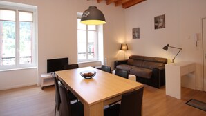 Una sala de estar moderna con techo de madera, una mesa de comedor con sillas, un sofá y una lámpara.