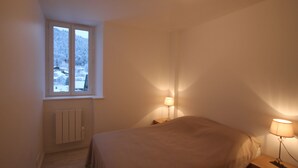 Un dormitorio con una cama individual, una ventana con vistas a un paisaje nevado y dos lámparas de noche.