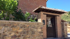 Un muro de piedra con un pequeño edificio de ladrillo y techo de tejas.