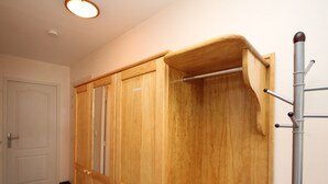 Een houten garderobe met spiegel en kapstok.