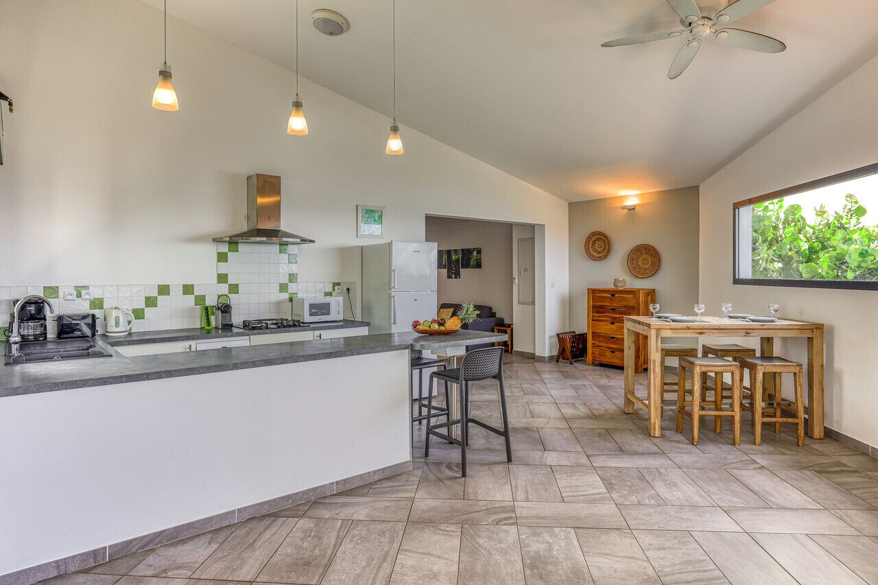 A modern kitchen with a central island, bar stools, and a dining table with chairs.