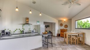 Una cocina moderna con una isla central, taburetes de bar y una mesa de comedor con sillas.