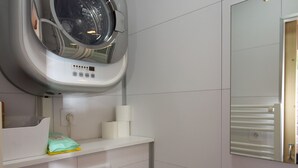 A modern bathroom with a built-in washing machine, a mirror, and a towel rack.