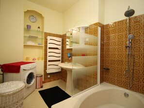 Ein Badezimmer mit Waschmaschine, Spüle, Dusche und Wandverkleidung mit Muster.