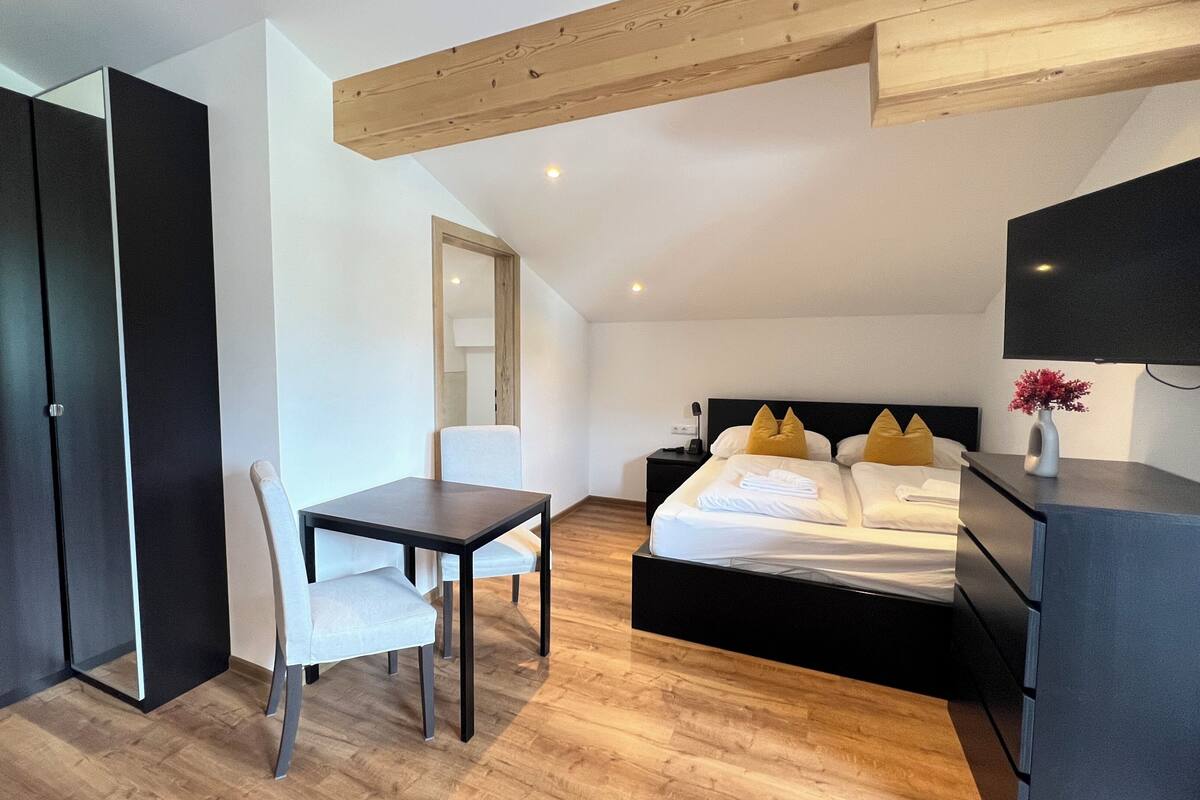 Une chambre d’hôtel moderne équipée d’un lit, d’un bureau, d’une chaise, d’une armoire et d’un téléviseur à écran plat.