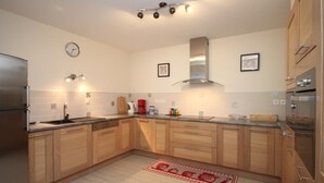 Une cuisine moderne avec des meubles en bois, un réfrigérateur en acier inoxydable, une cuisinière à gaz et un four encastré.