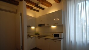 Una cocina compacta con armarios blancos, microondas y lavamanos.