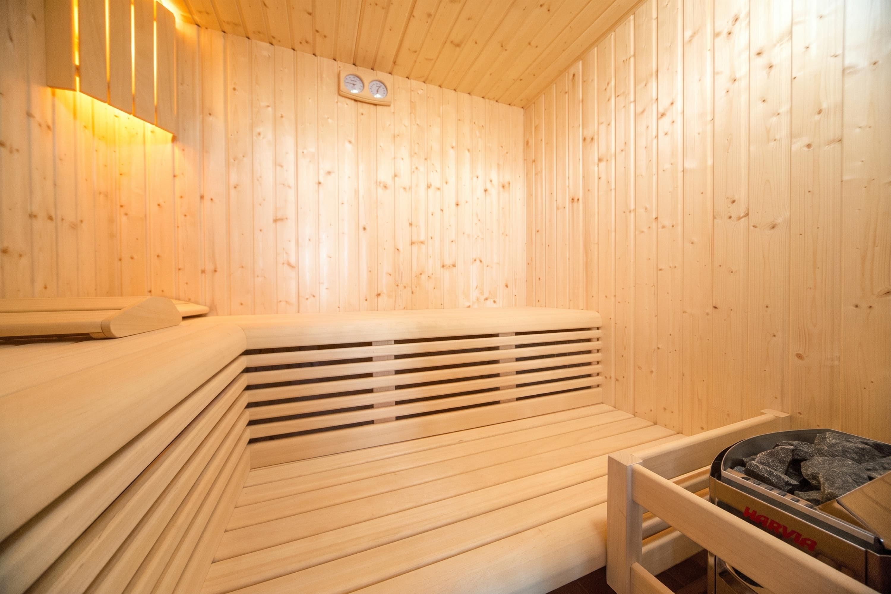 A sauna room with wooden walls, a bench, and a heater.
