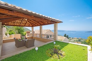 A covered outdoor seating area with wicker furniture, a stone wall, and a view of the sea. - Pool Villa Dia /w Sauna & Jacuzzi Near Dubrovnik (Dubrovnik)