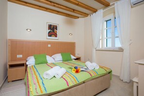 Ein Hotelzimmer mit Bett, Nachttisch, Fenster mit Vorhängen und einem Gemälde an der Wand.