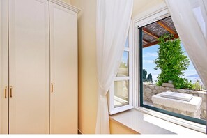 Una habitación con un ventanal grande, un armario blanco y una pared de piedra.