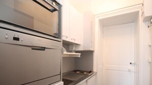 Una cocina compacta con horno empotrado, microondas y placa de cocina.