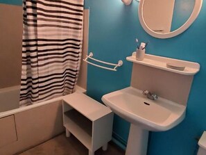 Une salle de bain avec un lavabo blanc, un miroir et un rideau de douche à rayures.