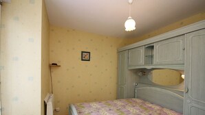A bedroom with a bed, a dresser, a radiator, and a hanging light fixture. - Mont-Dore: 2-room Apartment near Thermal Baths, Sleeps 4 (Mont-Dore)