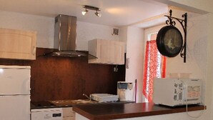 A compact kitchen with a stove, microwave, and a small refrigerator. There are two stools at the counter. - Central T2 near spa with wifi (Mont-Dore)