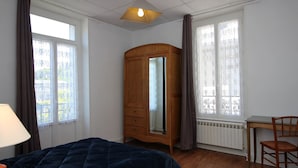 Een slaapkamer met een bed, een houten garderobe, een bureau en een stoel.