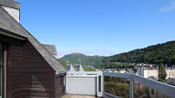 A balcony with a view of a town and mountains.