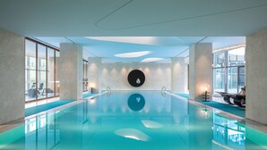 Una piscina interior moderna con agua cristalina, amplias ventanas y elementos de diseño contemporáneo.