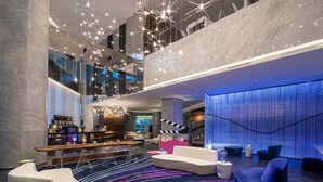 Un moderno vestíbulo de hotel con bar, zonas de estar y un nivel entre pisos.