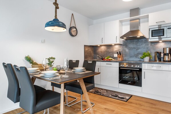 A modern kitchen with white cabinets, a built-in oven, and a microwave.
