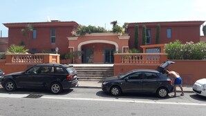 Ein Gebäude mit roter Fassade, einem zentralen Eingang mit Stufen und einem Schild mit der Aufschrift 'Le Prince des Isles 39'.