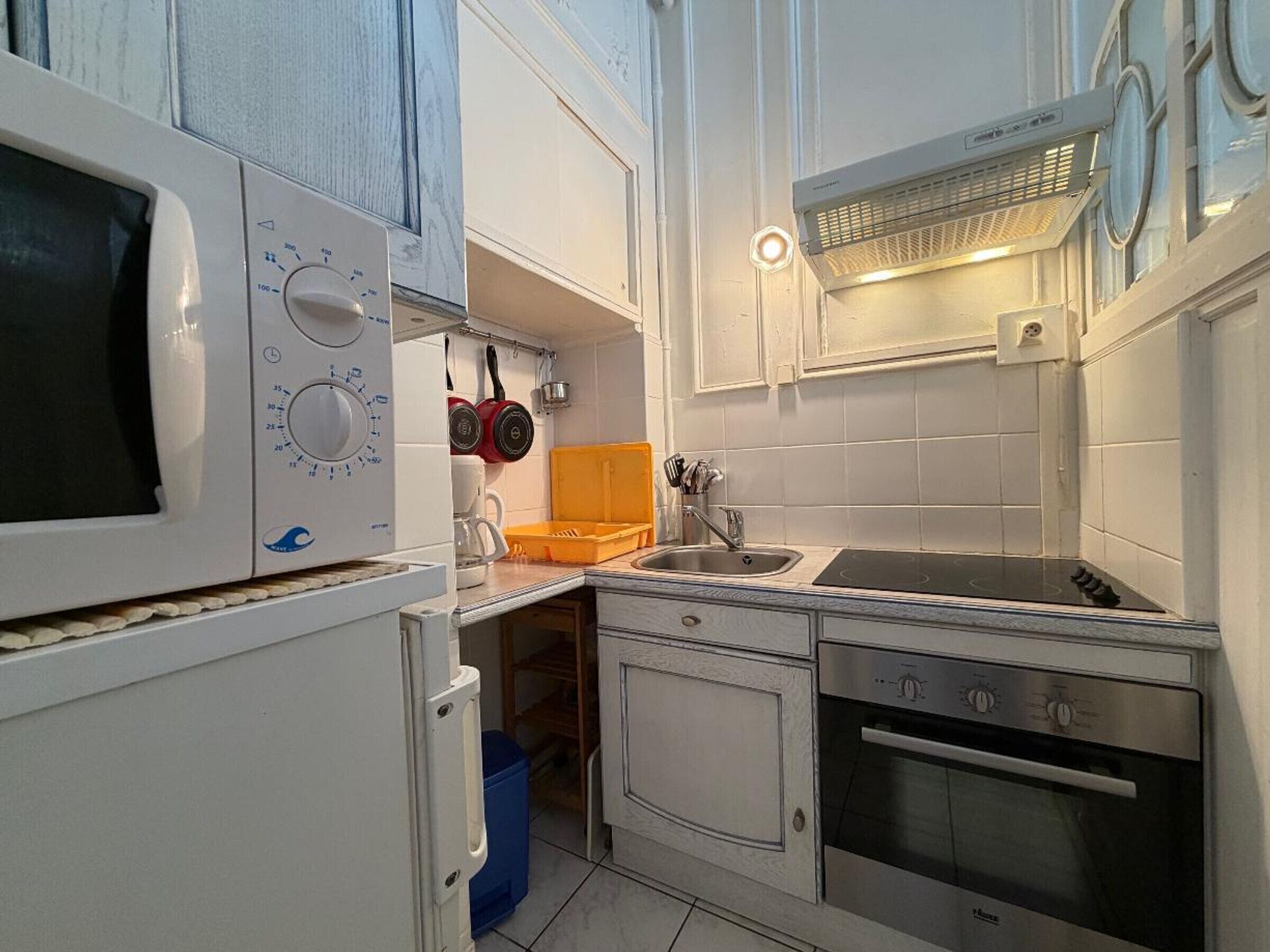 Una cocina compacta con microondas, horno, fregadero y una pequeña ventana.